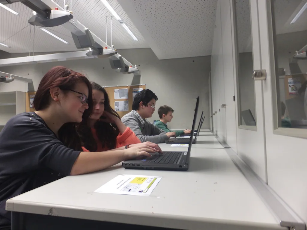 Jugendliche arbeiten an Laptops im Computerraum.